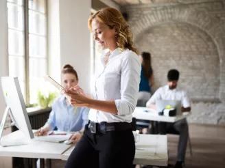 Woman using tablet with colleagues at desks