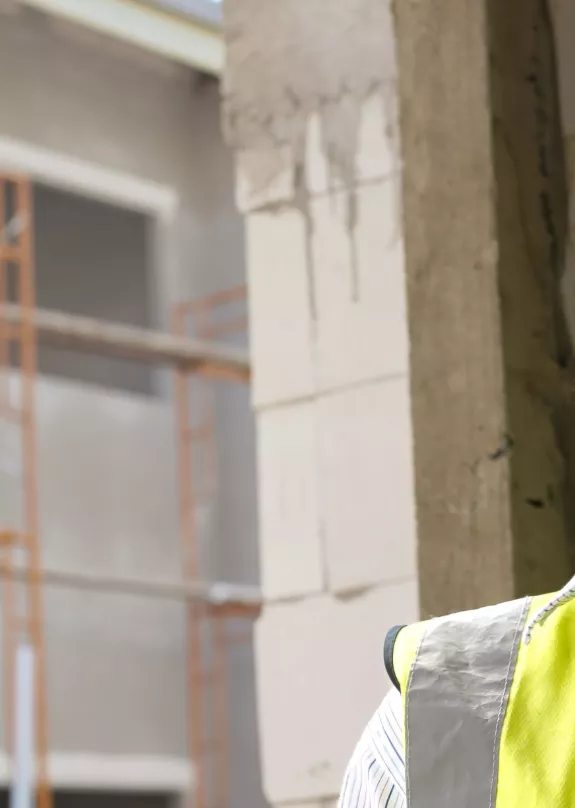 Engineer on a construction site using a phone and holding a tablet