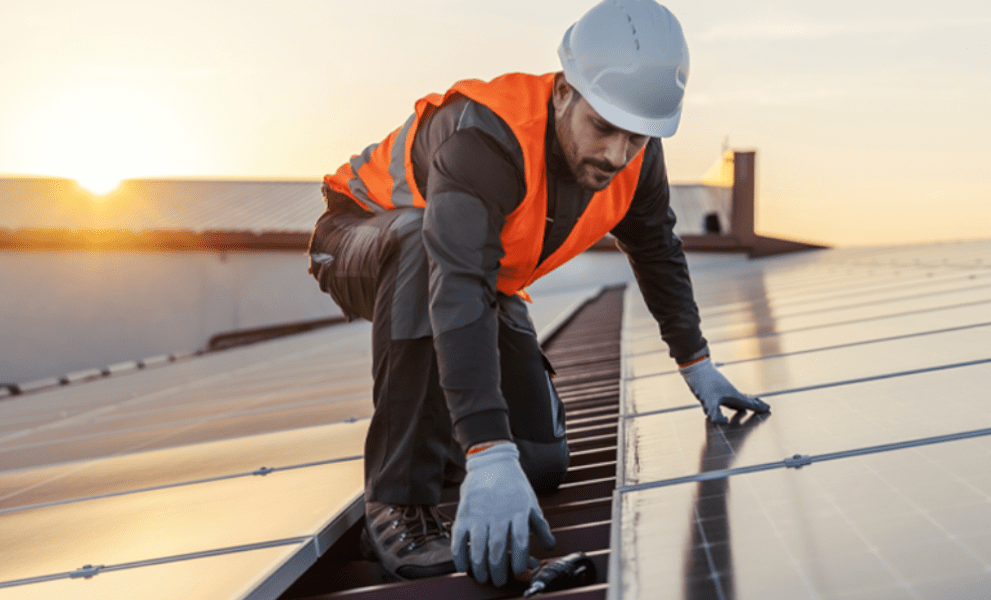 Man on rooftop installing solar panels